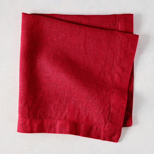 Flame HG Signature hand-dyed 22" square linen napkin in vibrant holiday red, folded on a light surface.
