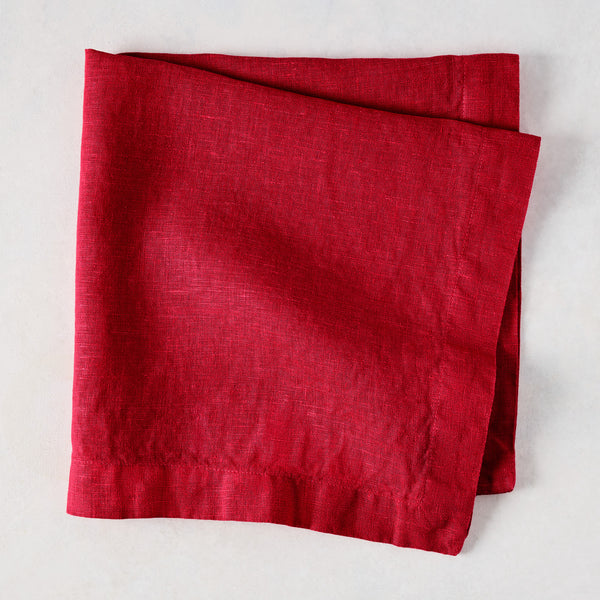 Flame HG Signature hand-dyed 22" square linen napkin in vibrant holiday red, folded on a light surface.