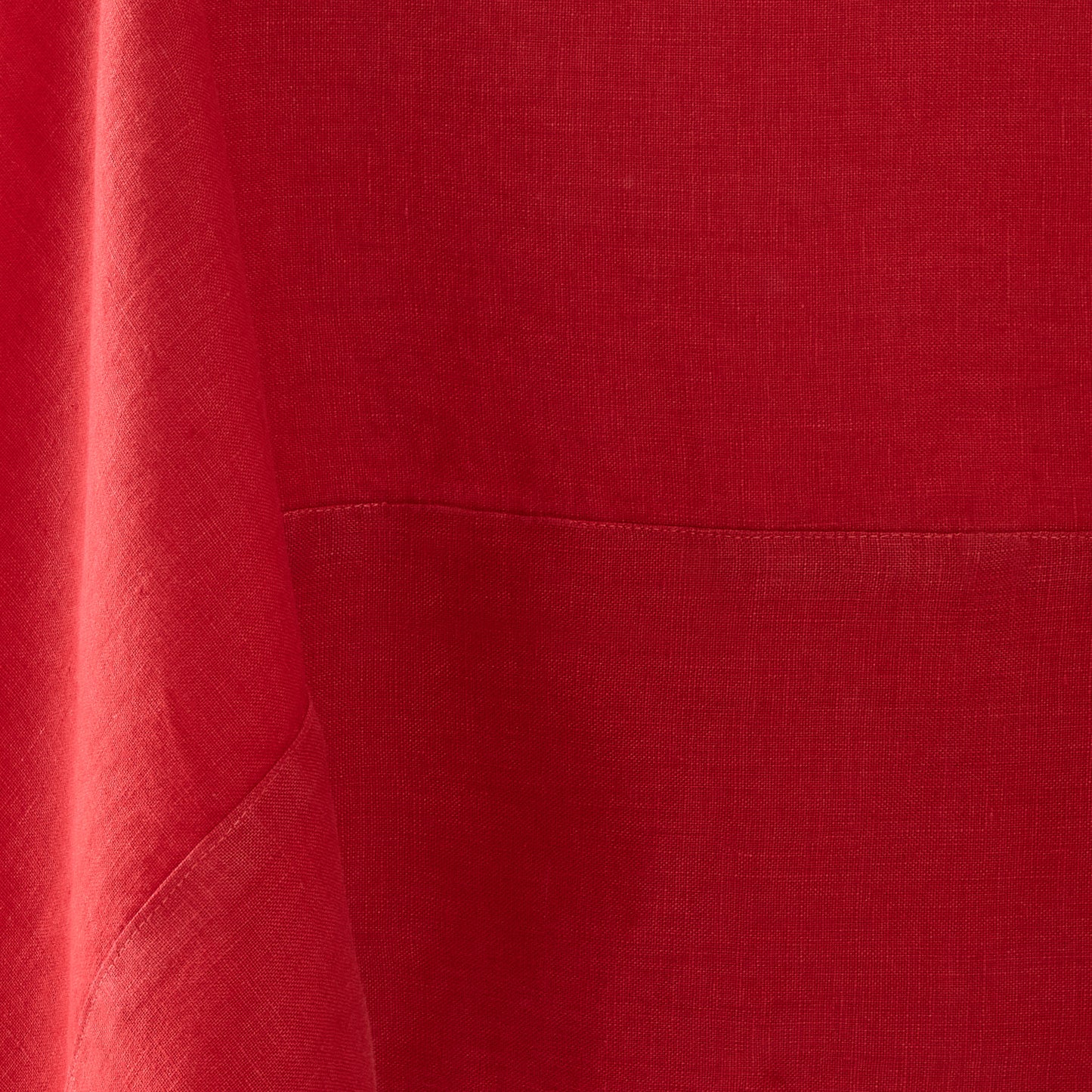 Flame red hand-dyed linen tablecloth with visible fabric texture and a stitched mitered border detail.
