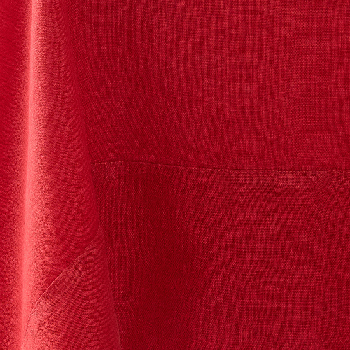 Flame red hand-dyed linen tablecloth with visible fabric texture and a stitched mitered border detail.