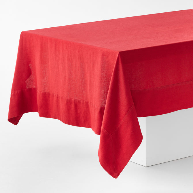 Flame red hand-dyed 100% linen tablecloth with a wide border and mitered corner detailing on a white table.