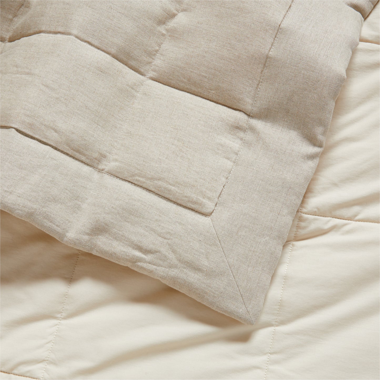 Flax linen quilted coverlet in natural beige, showing a corner fold and textured stitching.