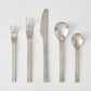 Flint 5-piece flatware set in polished 18/10 stainless steel with a modern, minimalist, rounded design.