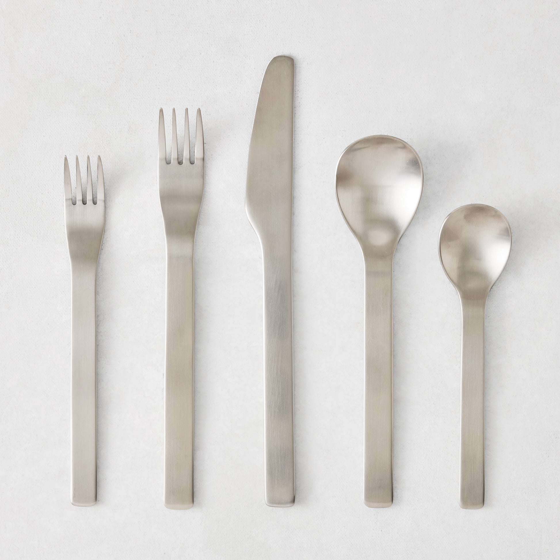 Flint 5-piece flatware set in polished 18/10 stainless steel with a modern, minimalist, rounded design.
