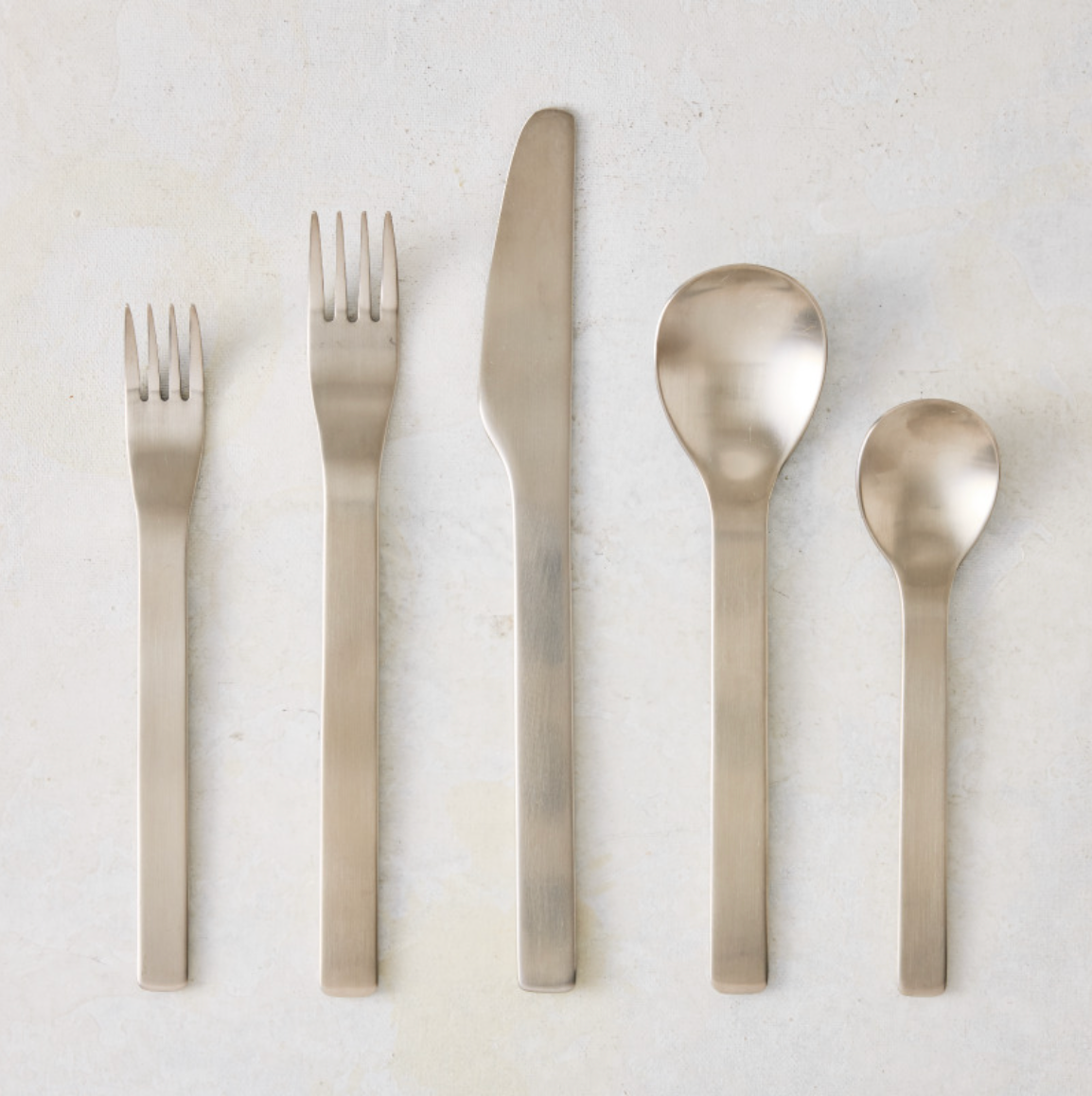 Flint 5-piece flatware set in polished 18/10 stainless steel with a modern, minimal, and rounded design.