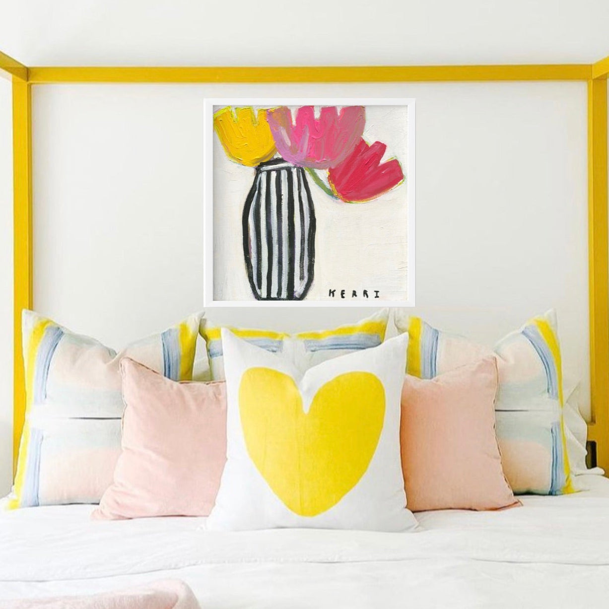 Kerri Rosenthal's "Flower Me" art print: bold yellow and pink flowers in a striped vase, framed above a bed.