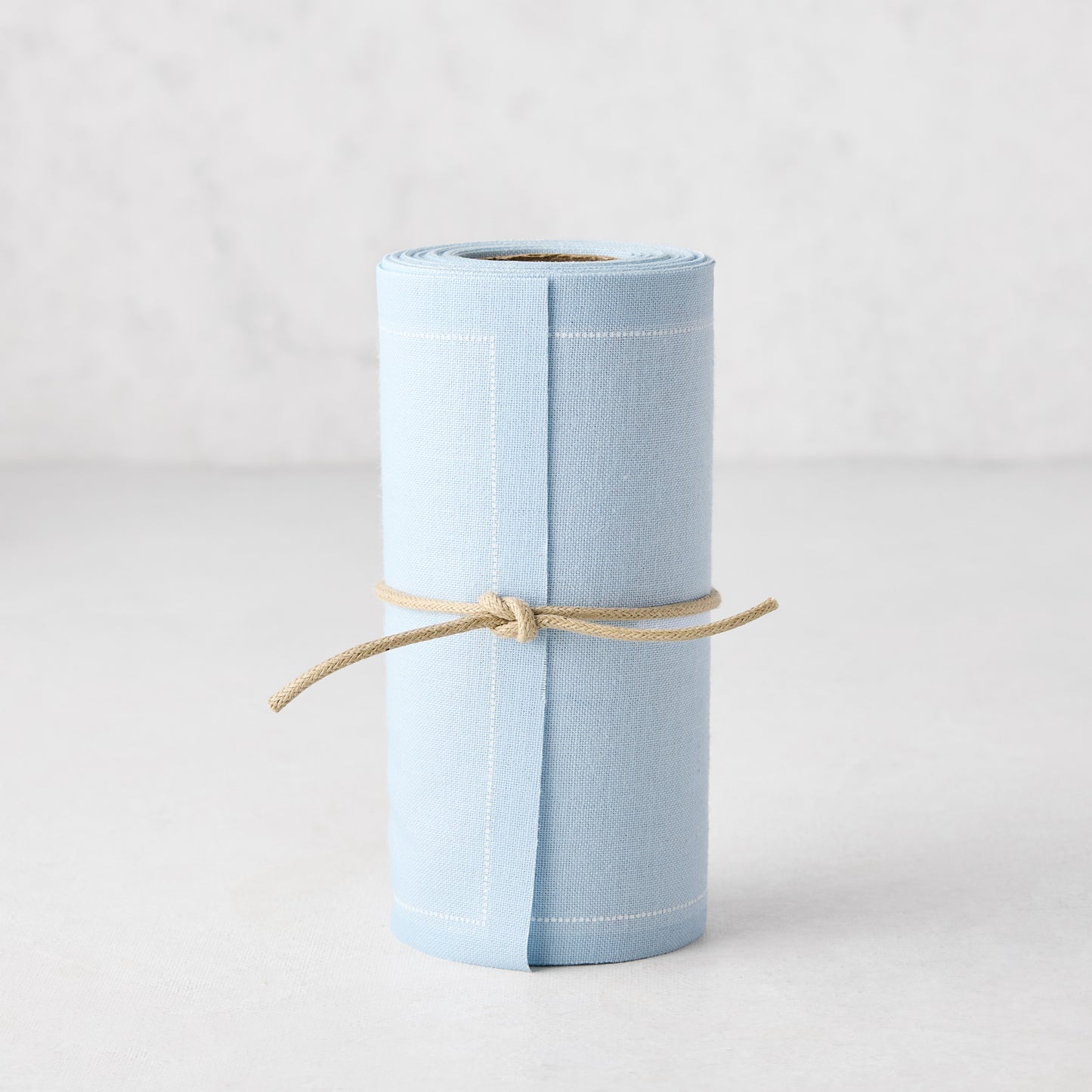 Roll of 50 Foggy Blue tear-off cotton cocktail napkins, tied with natural twine.