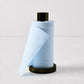 Foggy blue cotton tear-off napkins on a black metal holder, 5-inch height, minimalist bar accessory.