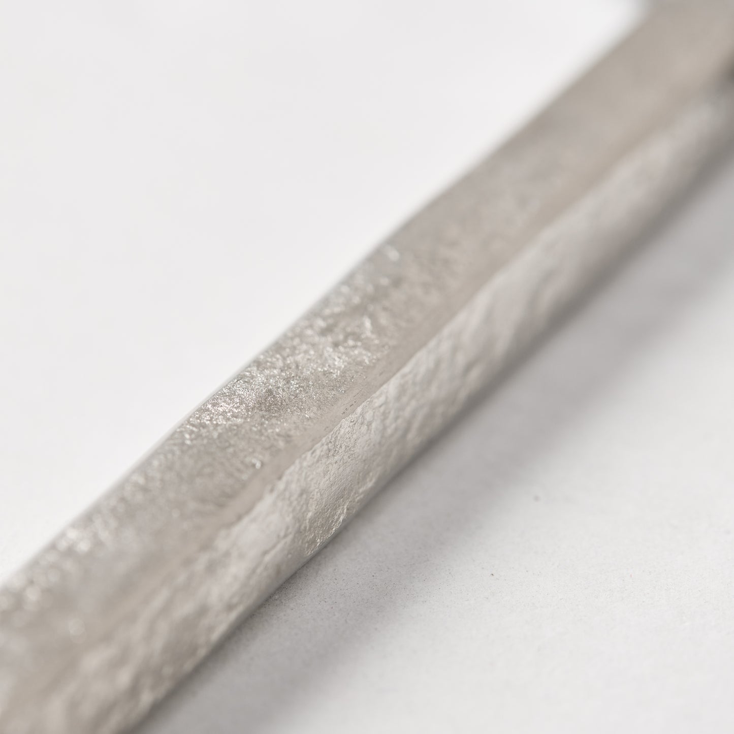Close-up of a silver forged stainless steel cheese knife handle with a hammered texture.