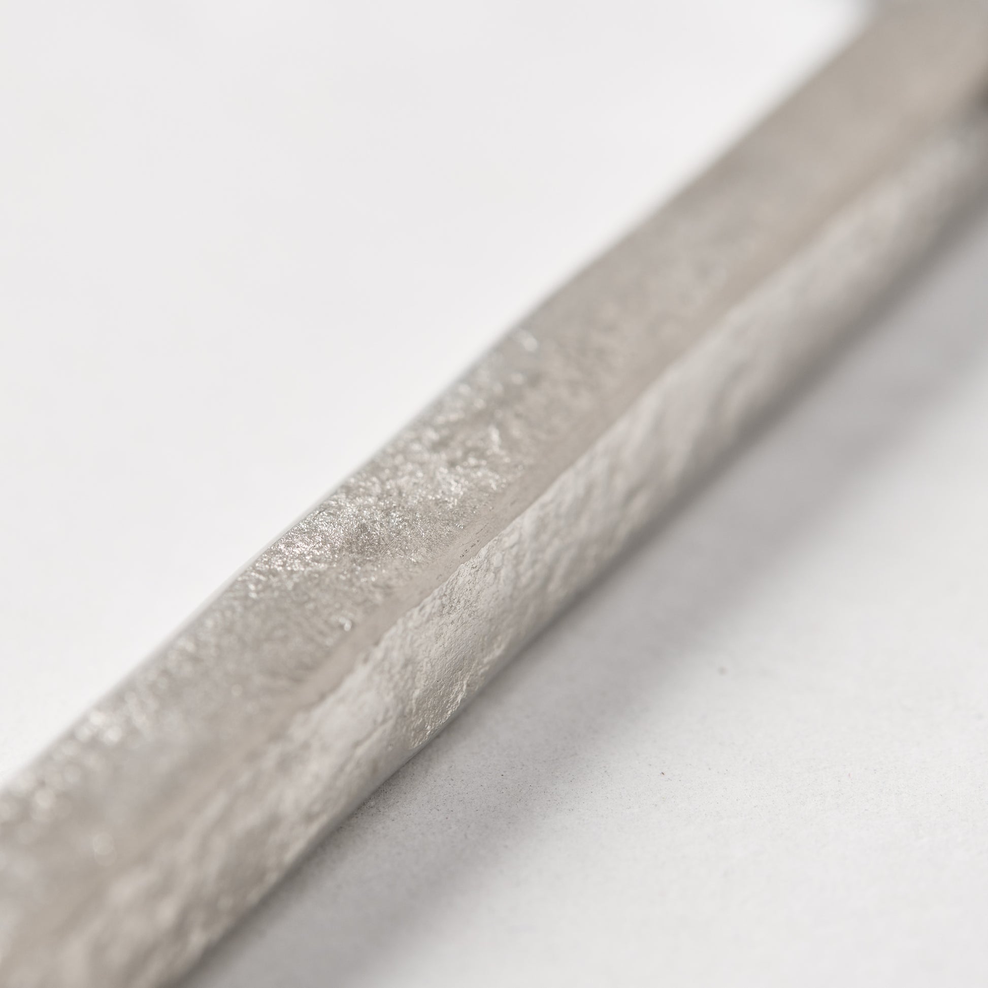 Close-up of a silver forged stainless steel cheese knife handle with a hammered texture.