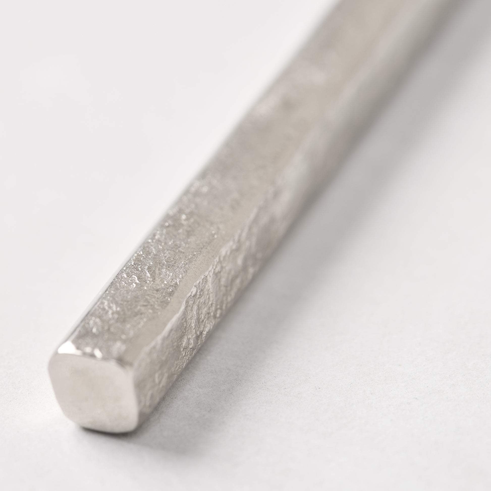 Close-up of a silver forged stainless steel cheese knife handle with a hammered texture.