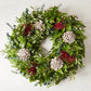 Fresh Eucalyptus Rain Wreath with green leaves, red berries, and light brown enchinops flowers.