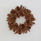 Handmade holiday wreath crafted from natural brown pinecones on a plain white background.