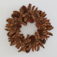 Handmade holiday wreath crafted from natural brown pinecones on a plain white background.