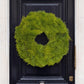 Fresh 24-inch cedar wreath with feathery green foliage hanging on a dark black front door.