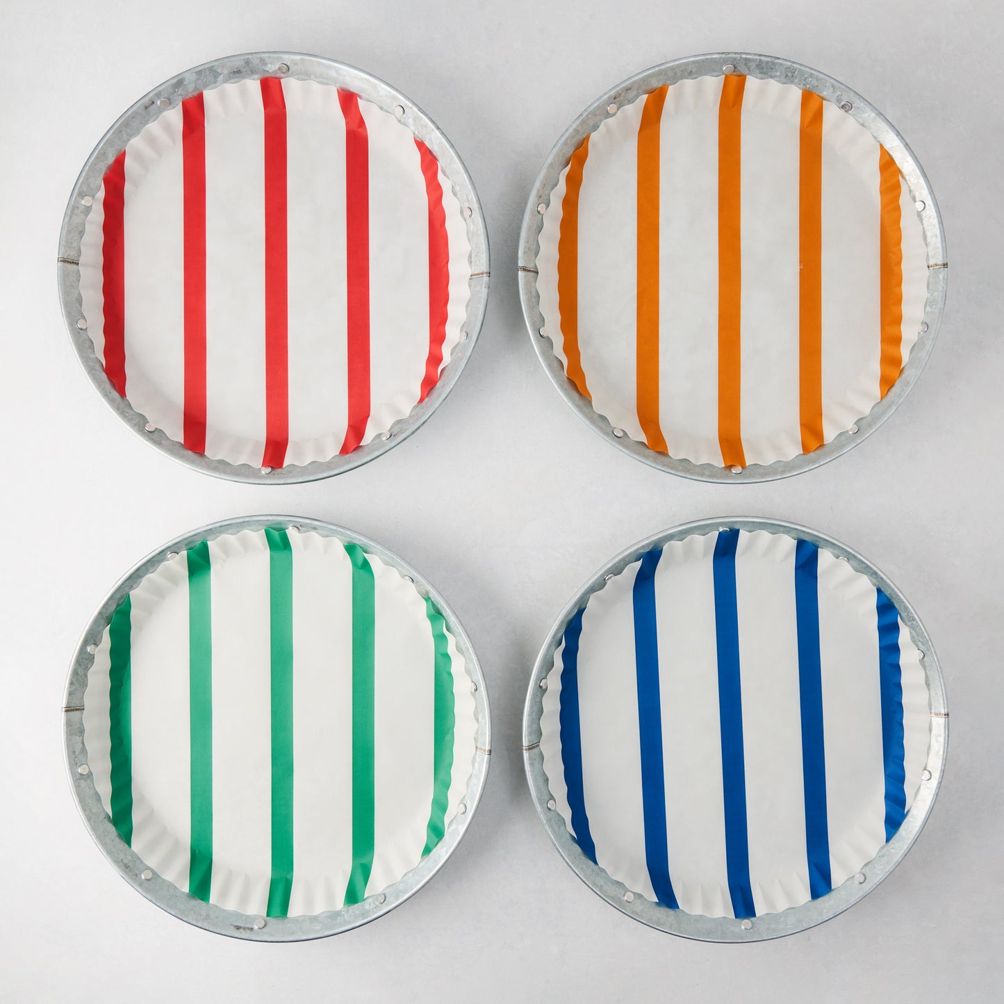 Set of 4 galvanized metal plates with colorful striped parchment liners: red, orange, green, and blue.