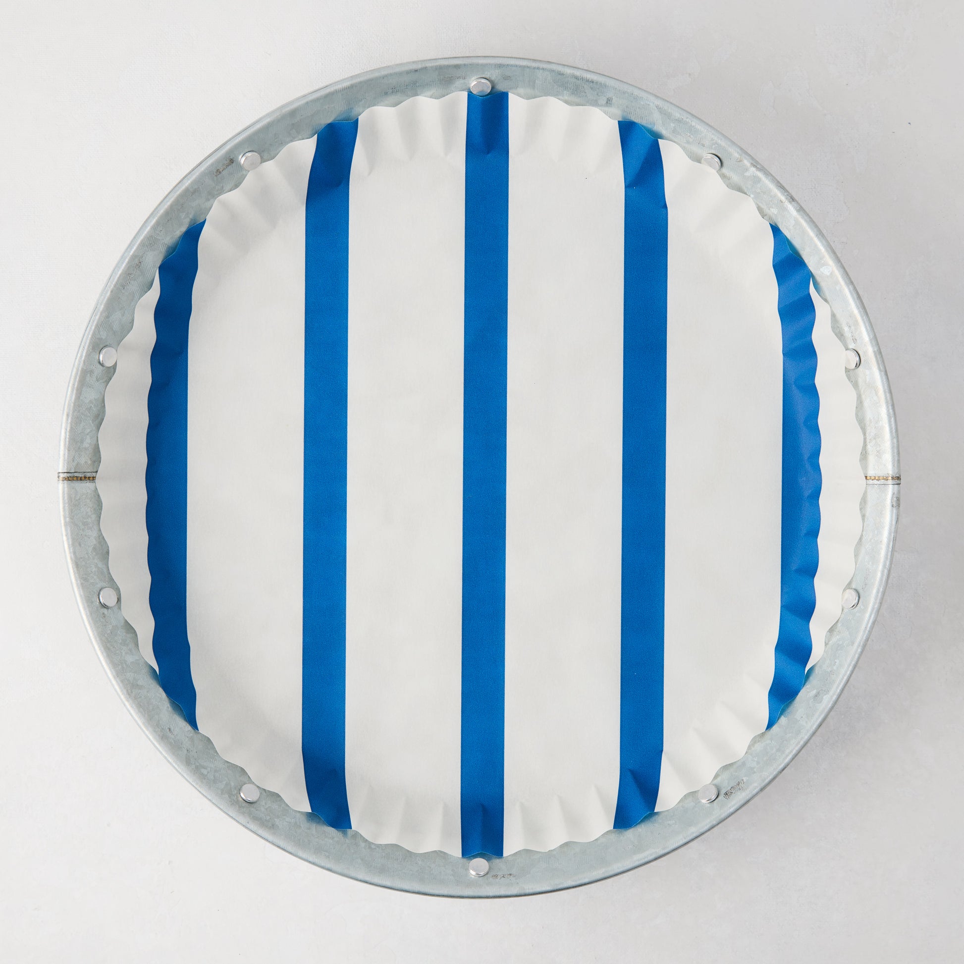 Galvanized metal plate with a white and blue striped parchment liner, top-down view.