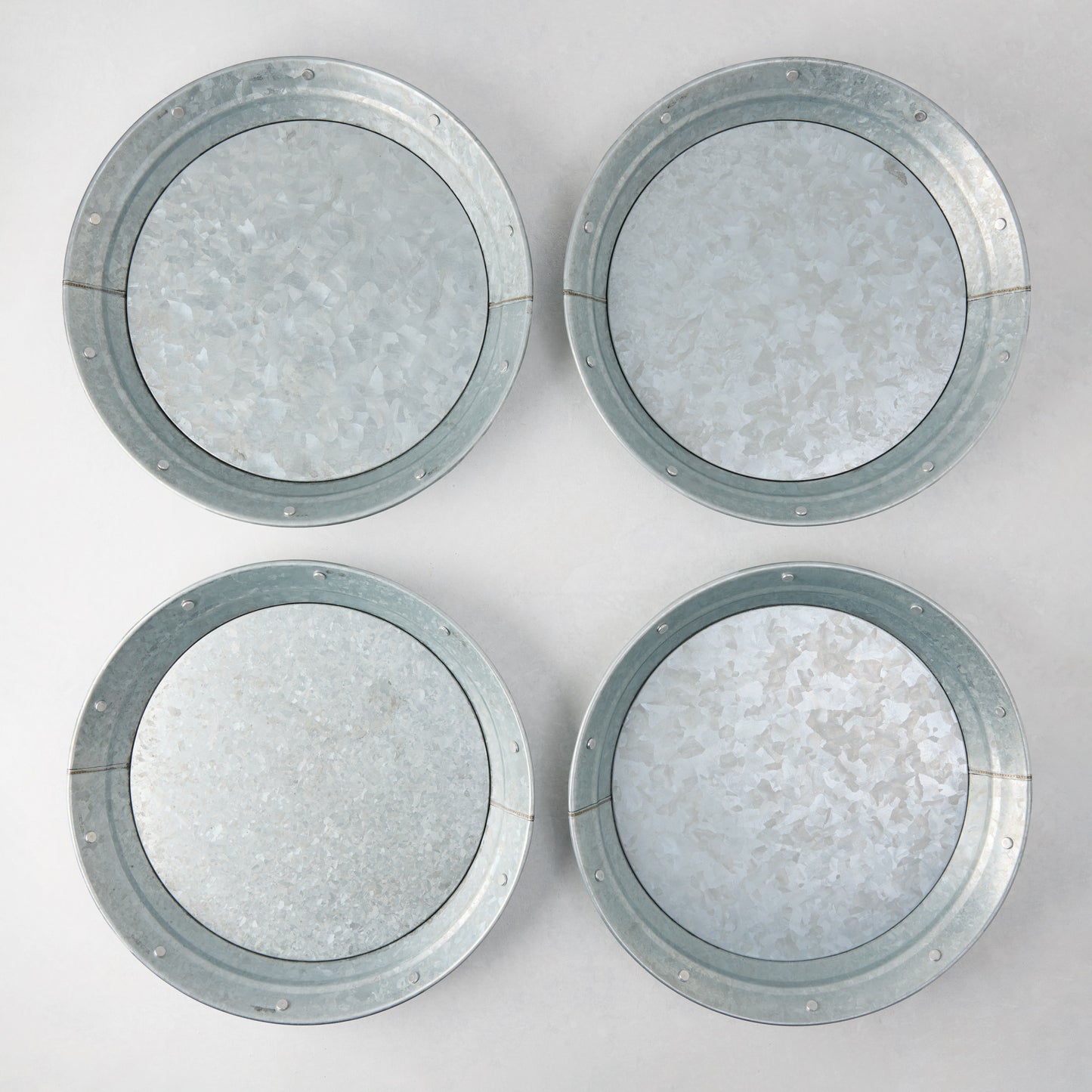 Set of 4 round galvanized metal plates with riveted edges, 12.75" diameter.