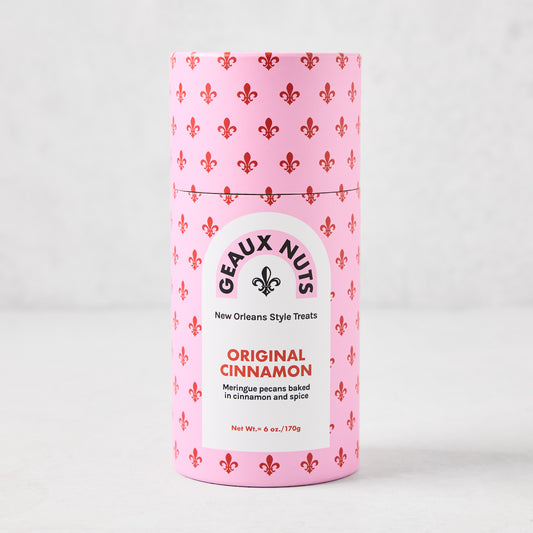 Geaux Nuts Original Cinnamon Pecans in a pink cylindrical container with red fleur-de-lis pattern.