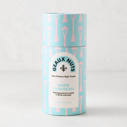 Geaux Nuts White Chocolate Pecans in a blue paper tube with pink streetlamp pattern.