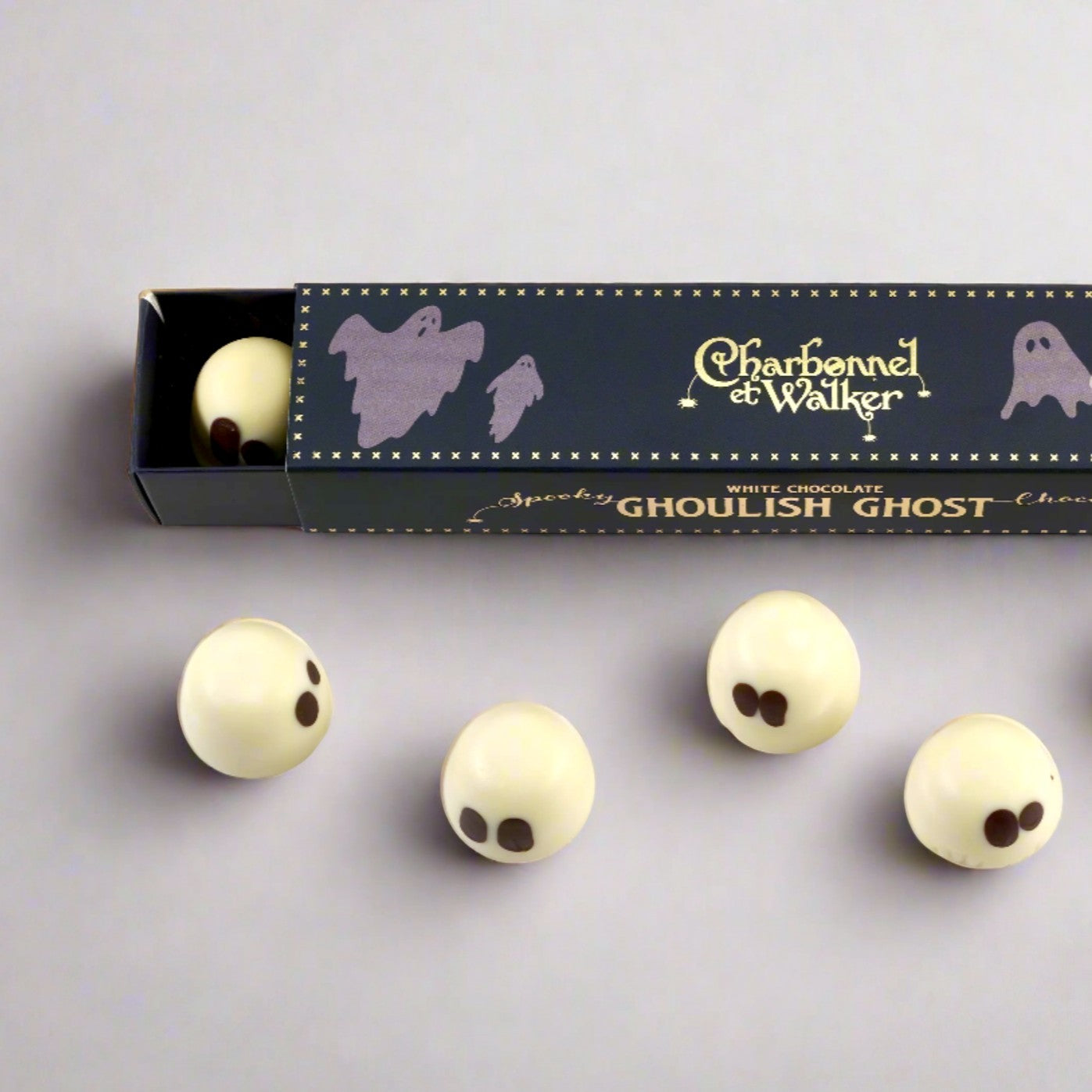 Charbonnel et Walker white chocolate ghost truffles with dark chocolate eyes, presented in a navy blue Halloween box.