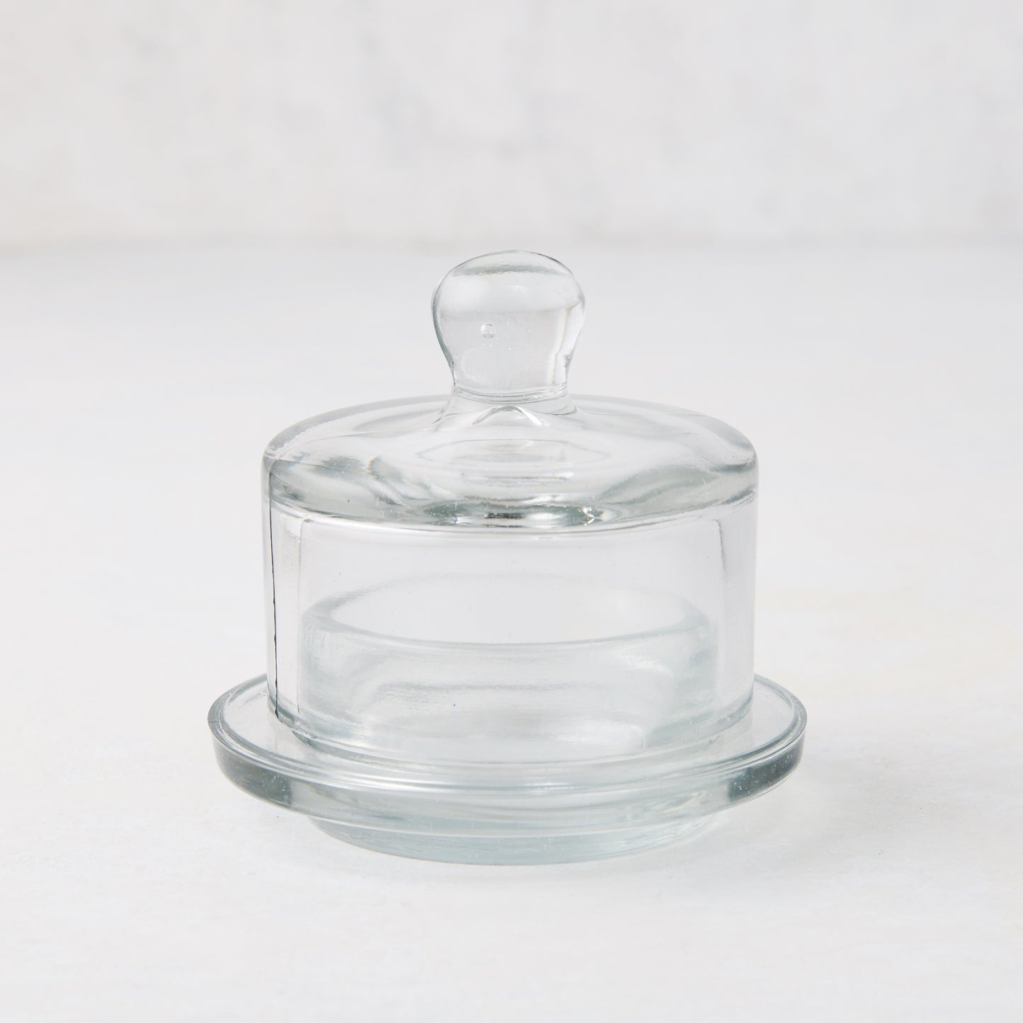 Clear glass butter dish with domed lid and small knob handle on a round base.