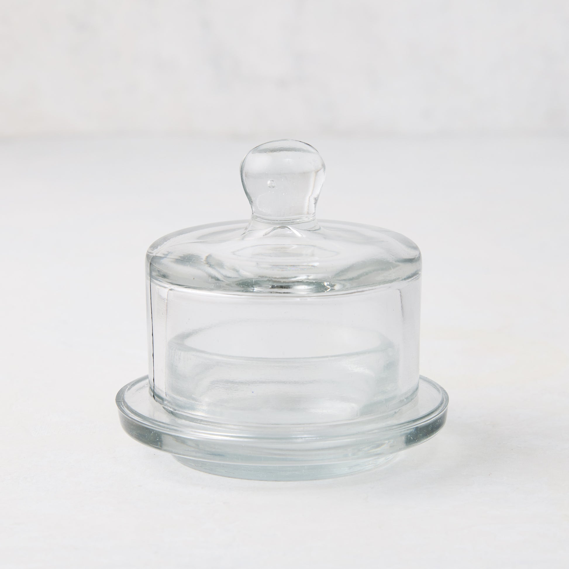 Clear glass butter dish with domed lid and small knob handle on a round base.