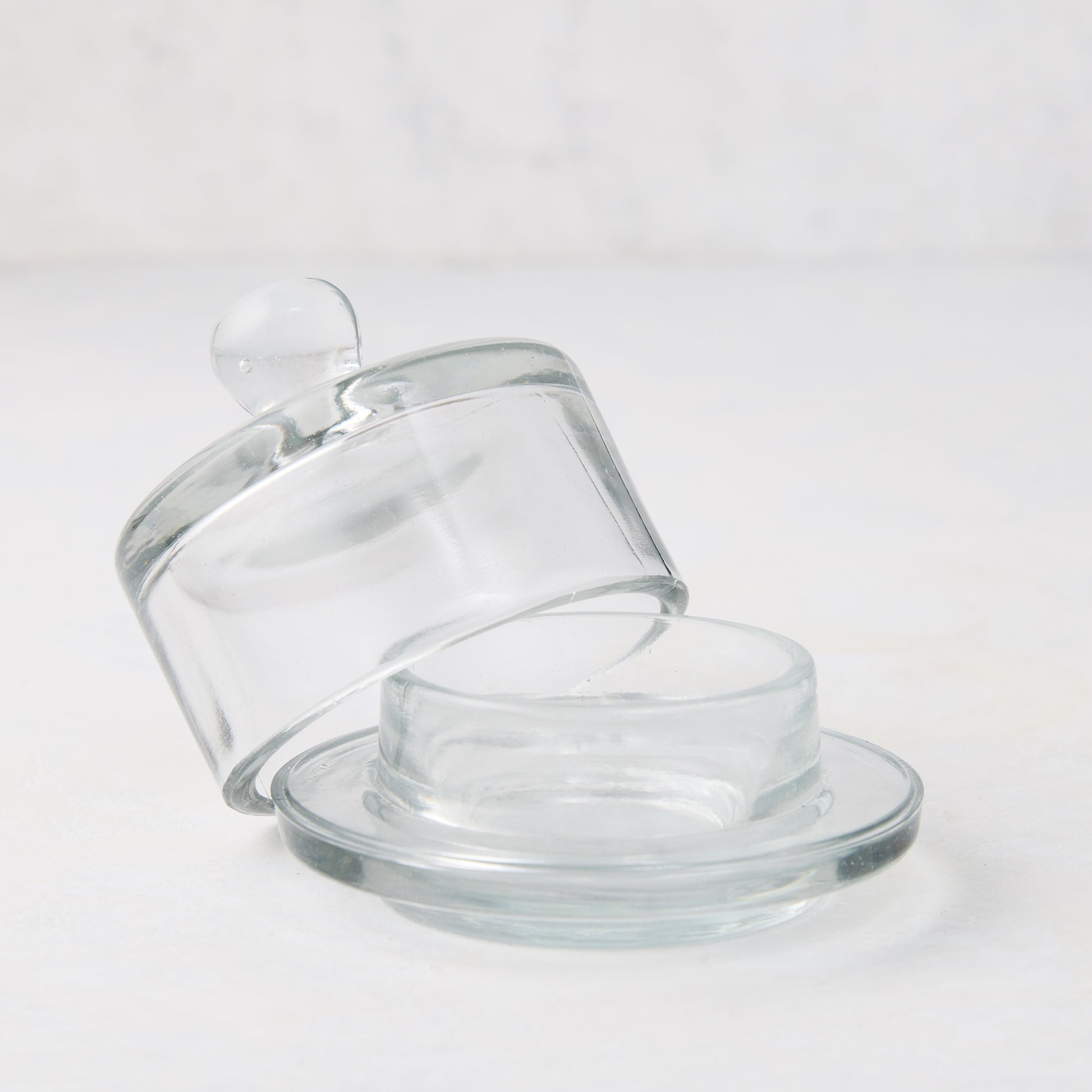 Clear glass butter dish with a domed lid and small knob, resting on a round base.