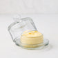 Clear glass butter dish with a domed lid and knob, holding yellow butter.