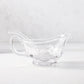 Clear glass gravy boat with handle, spout, and small glass ladle.