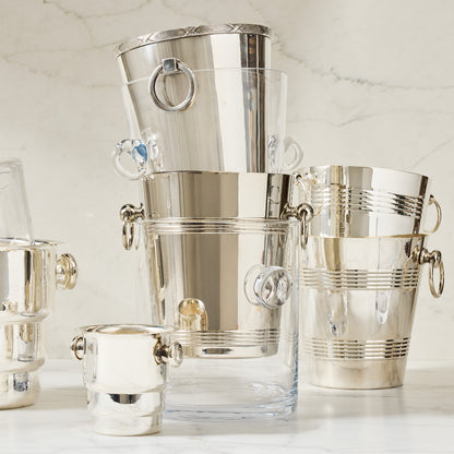 Stacked glass and silver ice buckets with knob handles on a marble surface.
