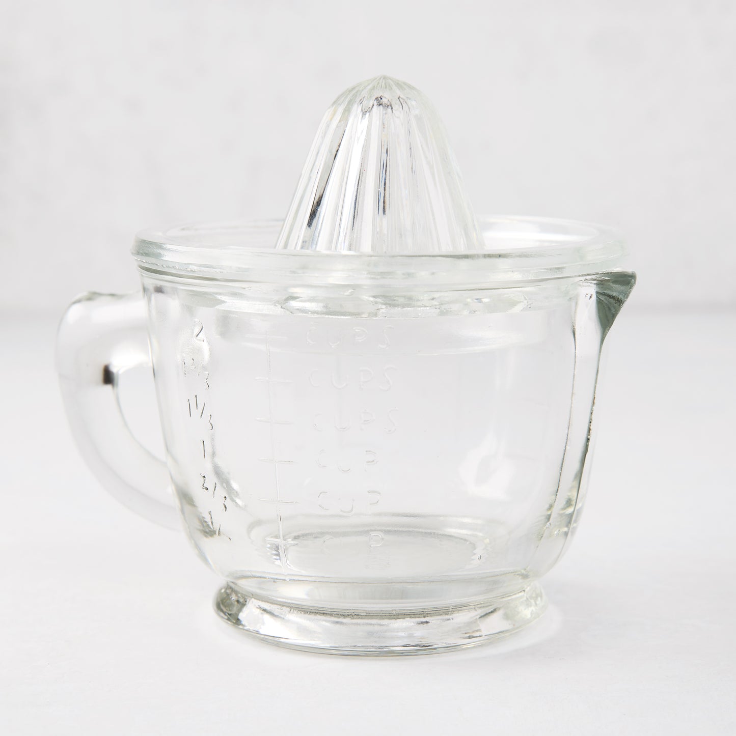 Clear recycled glass juicer with ribbed cone, handle, spout, and engraved measurements.