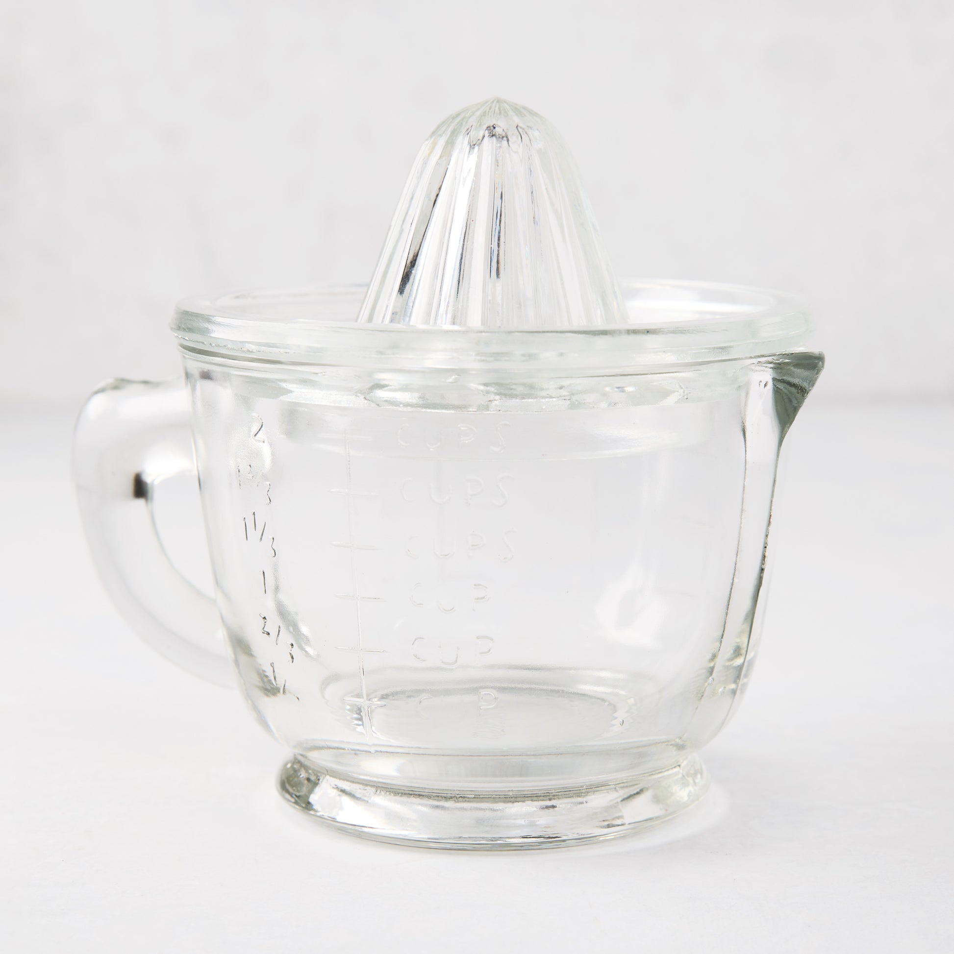 Clear recycled glass juicer with ribbed cone, handle, spout, and engraved measurements.