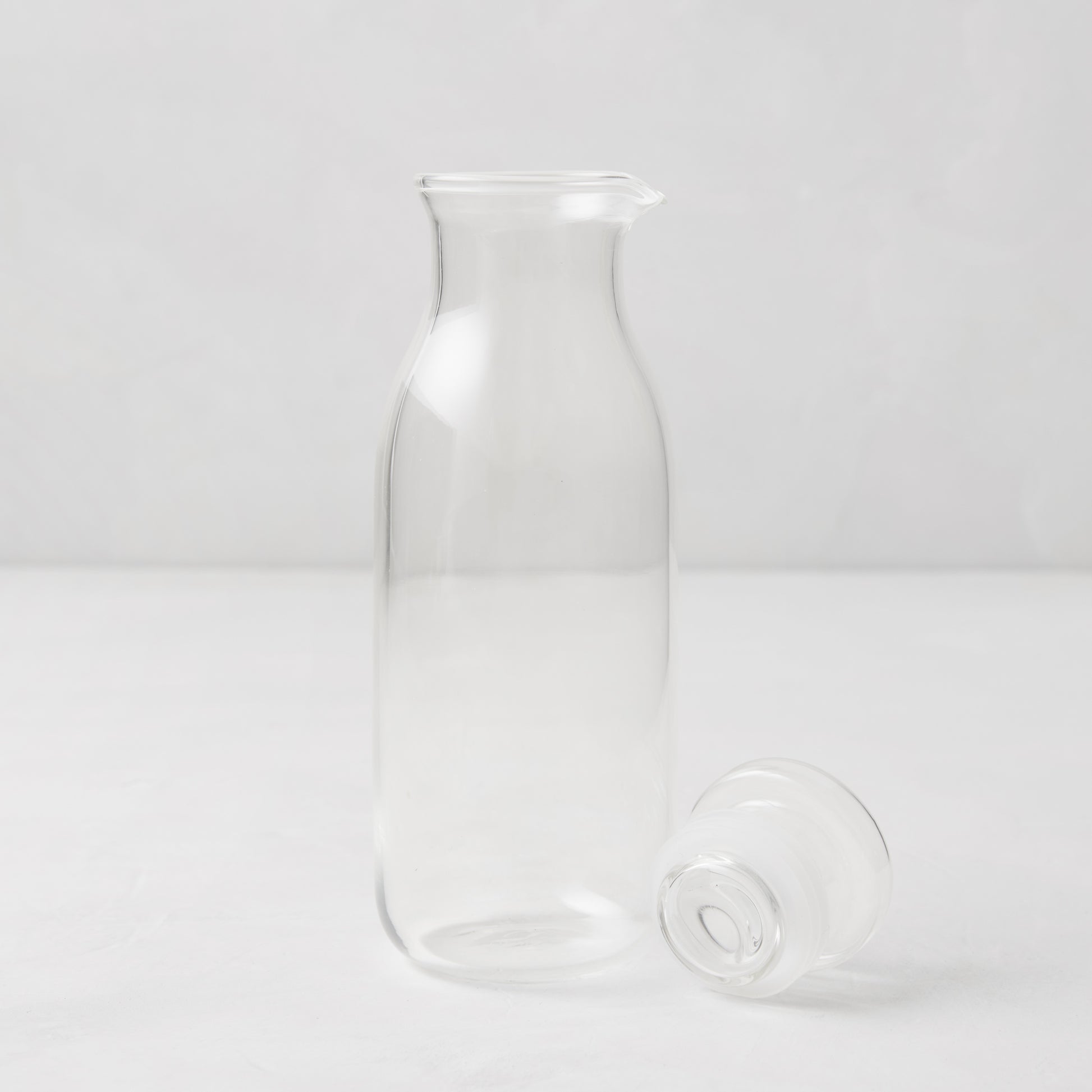 Clear 9 oz glass salad dressing bottle with a spout and a silicone stopper lying beside it.
