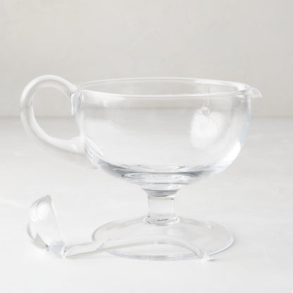 Clear glass sauce/gravy boat with handle, spout, pedestal base, and matching glass ladle.