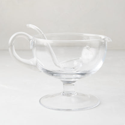 Clear glass sauce/gravy boat with handle, spout, pedestal base, and matching glass ladle.