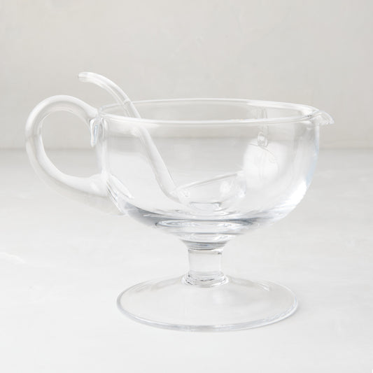 Clear glass sauce/gravy boat with handle, spout, pedestal base, and matching glass ladle.