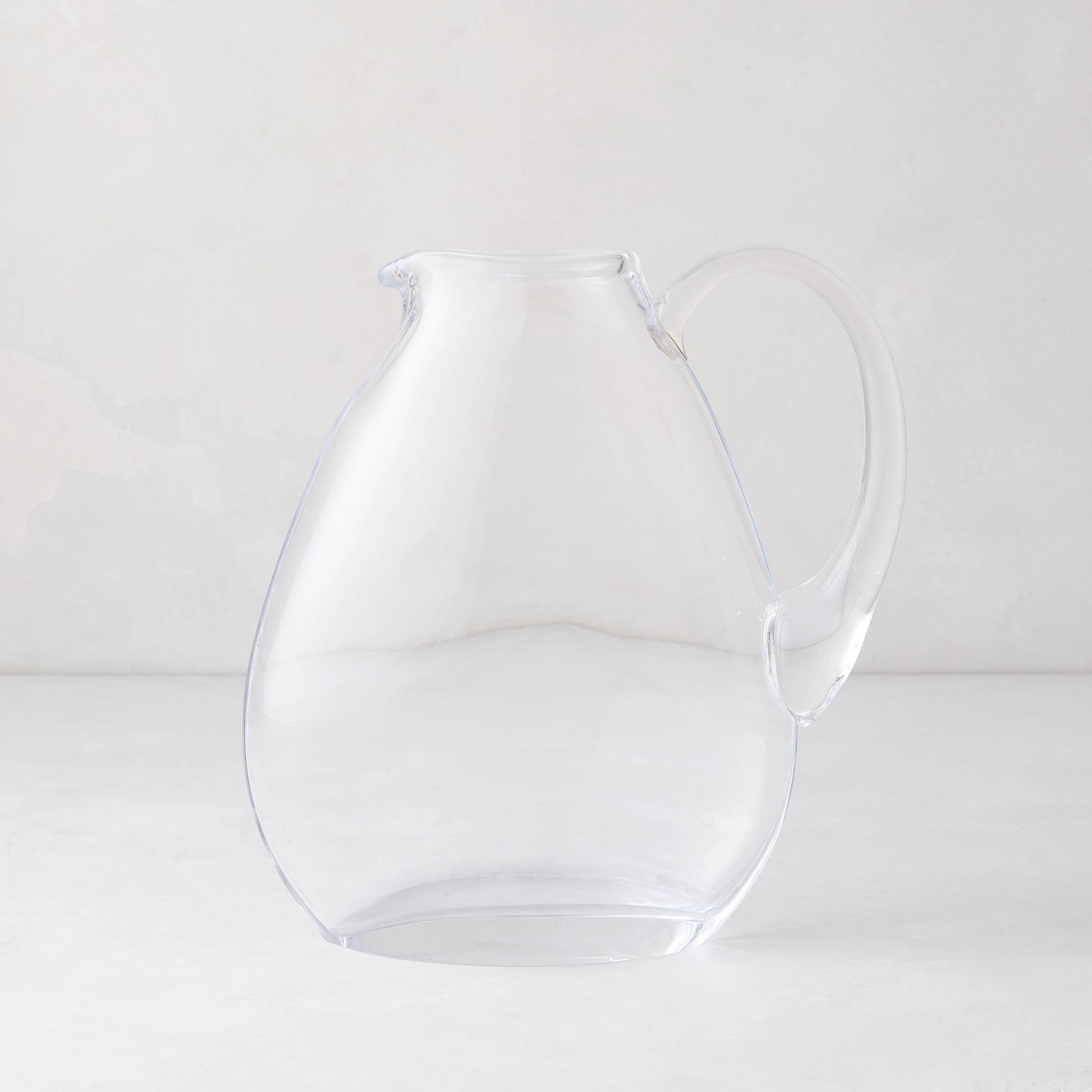 Clear mouth-blown glass teardrop pitcher with handle, 84.5oz, on a light background.