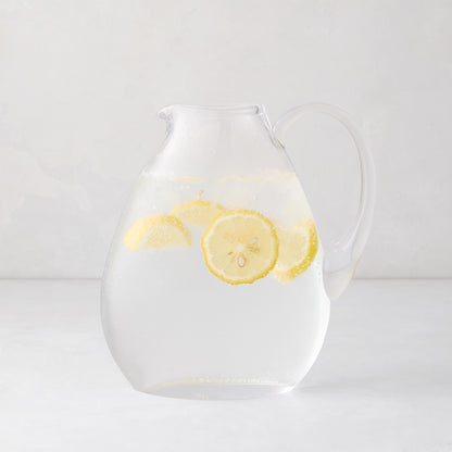 Clear glass teardrop pitcher filled with water and lemon slices, mouth-blown in Poland.