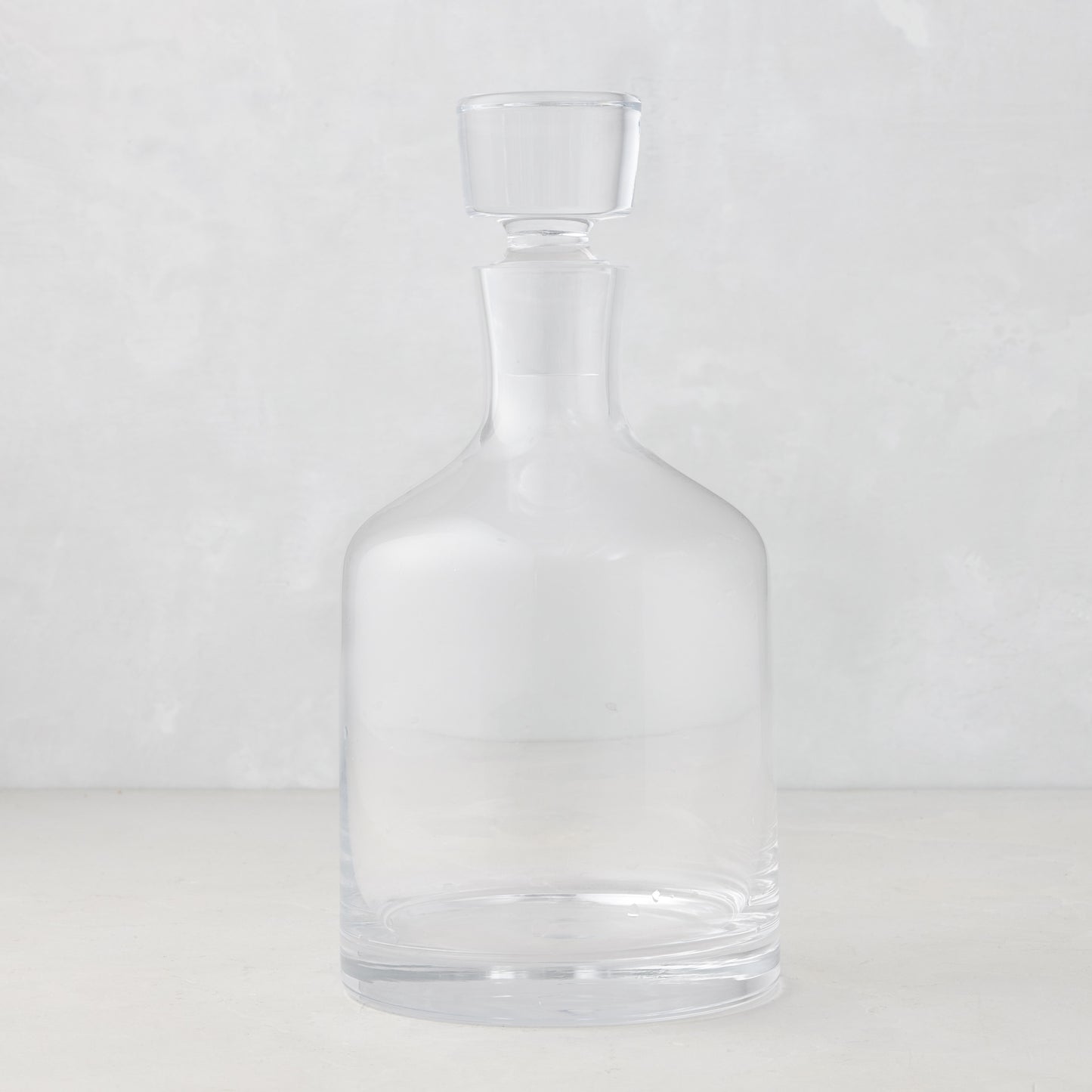 Clear mouth-blown glass wine and whiskey decanter with broad base and curved neck, 10.25"H.