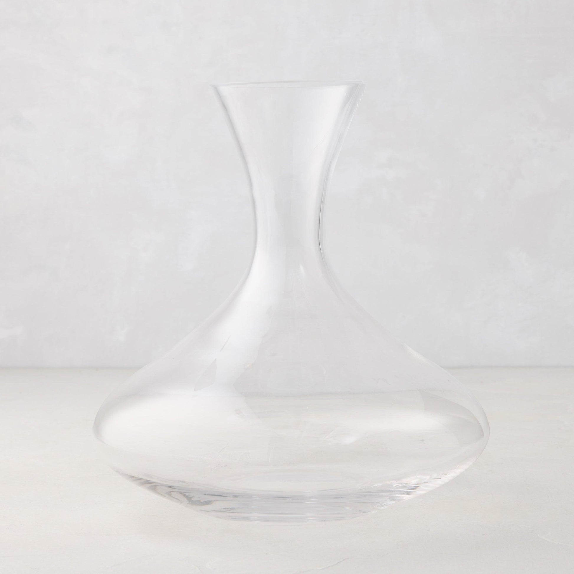 Clear mouth-blown glass wine carafe, 50 oz, with a broad base and curved neck.