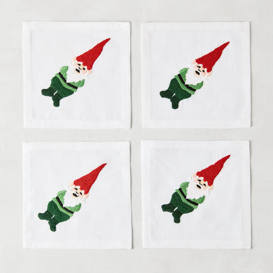 Set of 4 white linen 5.5" square cocktail napkins with embroidered gnomes in red hats and green outfits.