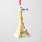 Gold glittered glass Eiffel Tower Christmas ornament with a Joyeux Noel sign, 5.75 inches tall.