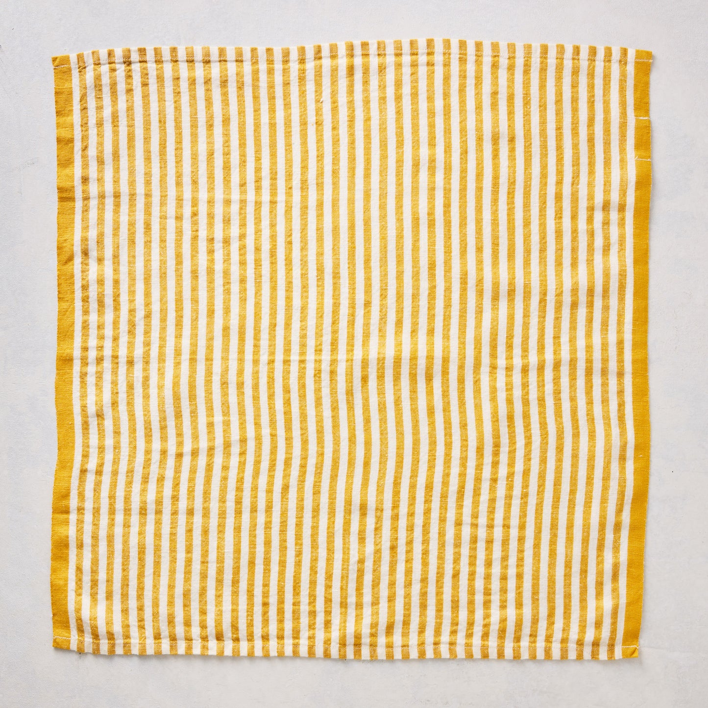 21-inch square linen napkin with golden yellow ticking stripes on a white base and a solid yellow border.