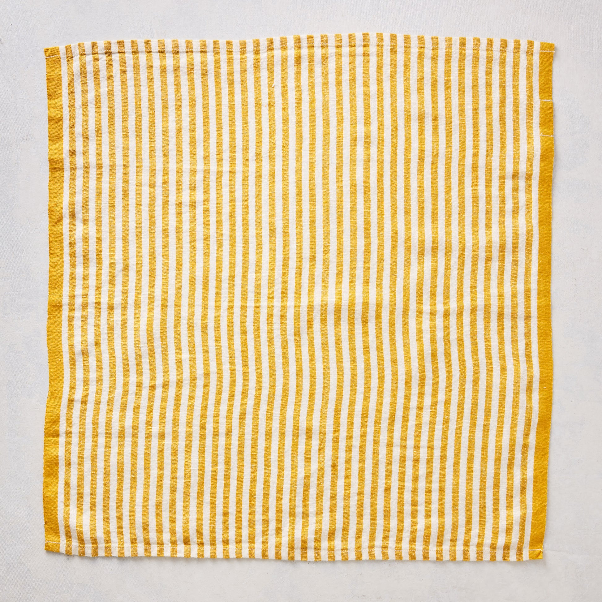 21-inch square linen napkin with golden yellow ticking stripes on a white base and a solid yellow border.