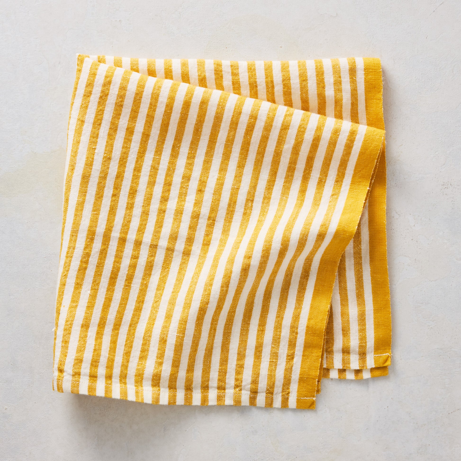 21-inch square cotton napkin with golden yellow and white ticking stripes and a yellow border.
