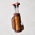 6-inch glass and resin golf bag Christmas ornament with miniature clubs, a red flag, and glittered bronze finish.