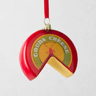 Red Gouda Cheese Wheel Christmas ornament with a slice removed, showing yellow cheese, hanging from a red ribbon.