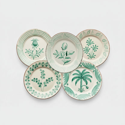Green Casa Nuno assorted ceramic dinner plates with hand-painted botanical designs.
