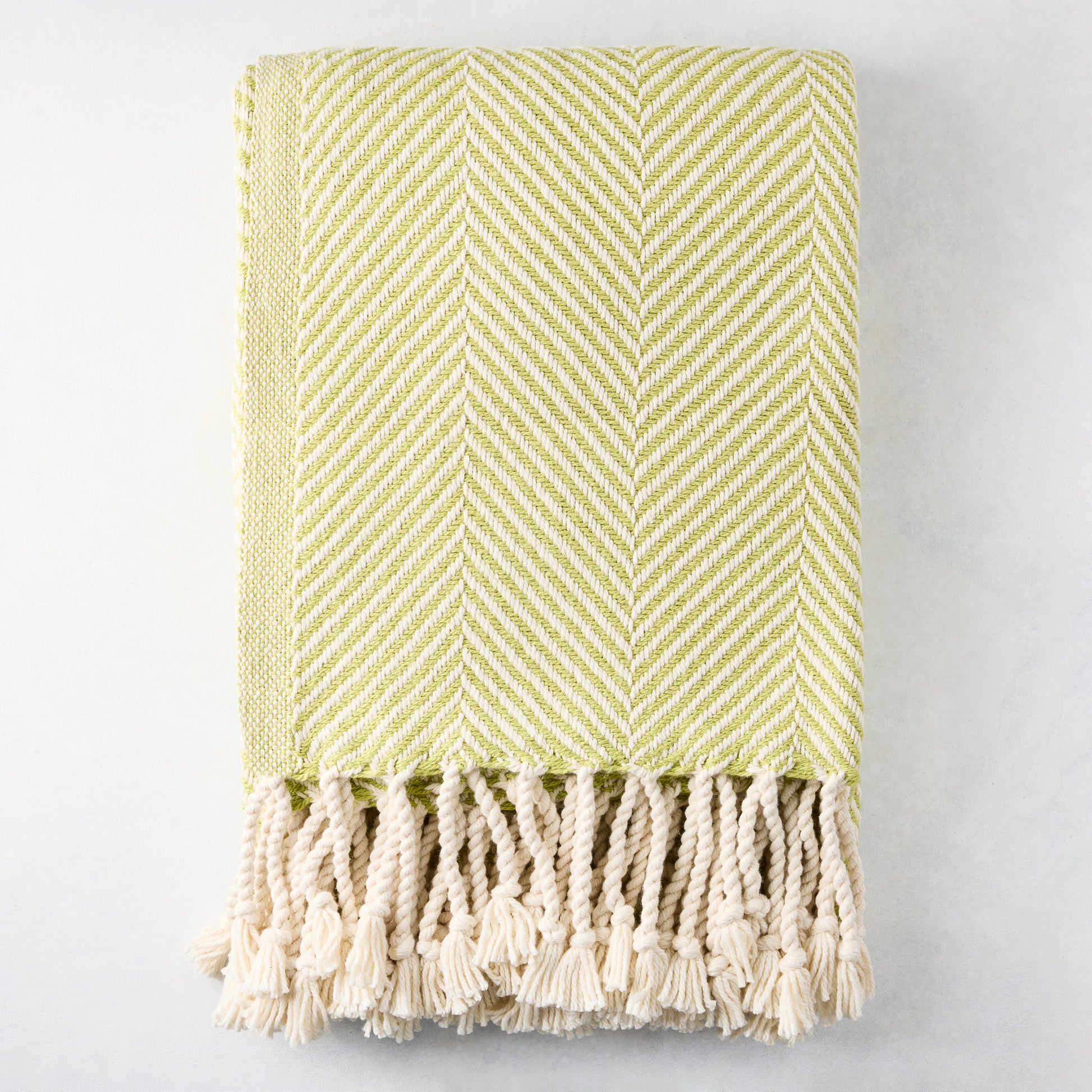 Green chevron cotton throw blanket with thick rope fringe.
